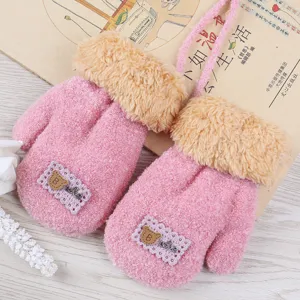 Detailed shot of pink kids plush winter gloves with cute bear patch and fuzzy cuffs.