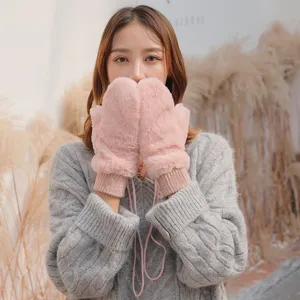 Closeup of winter plush fluffy pink mittens with hanging rope detail, cozy cold weather style.
