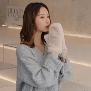 Close-up detail of soft fluffy winter mittens worn by model in cozy indoor setting.
