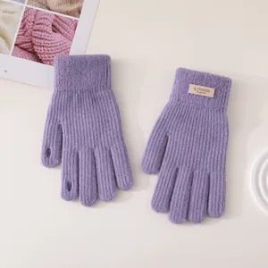 Purple knitted winter gloves with finger holes and stylish cuff tag for cold weather wear.