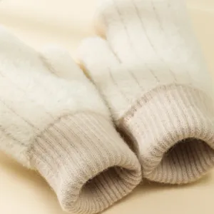 Primo piano di soffici mitten invernali in peluche con polsini a costine beige caldo.