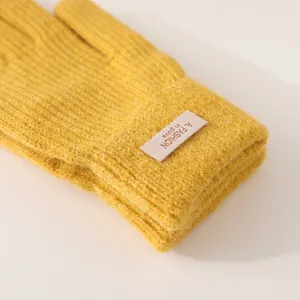 Detailed shot of yellow winter knitted gloves featuring cozy fabric and a stylish wrist tag.