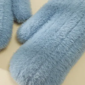 Primo piano dettagliato di guanti invernali in peluche blu soffici con calda consistenza.
