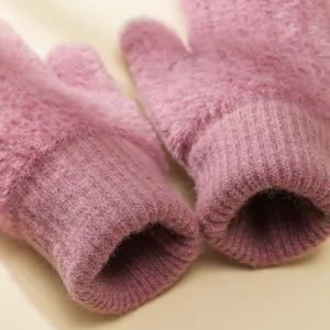 Primo piano di guanti invernali in peluche rosa con polsini a costine, morbidi e caldi.