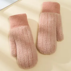 Primo piano di guanti invernali spessi e morbidi in peluche rosa con polsini a coste.