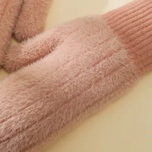 Primo piano di morbidi guanti invernali in maglia rosa soffice con texture peluche.