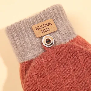 Close-up view of winter knitted warm glove cuff, showing texture, leather label and button detail.