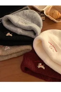 Primo piano di berretti in maglia con ricamo di cucciolo carino in vari colori, stile invernale.