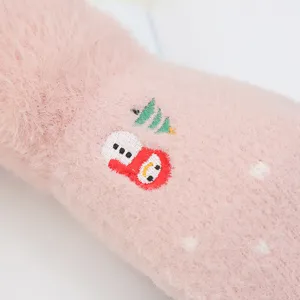 Primo piano dettagliato di guanti invernali rosa in peluche con ricamo di un simpatico pupazzo di neve.