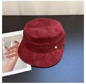 Detail view of burgundy faux suede cadet cap with gold heart charm, vintage equestrian hat.