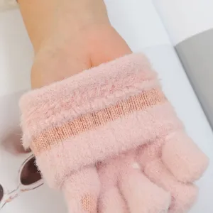 Primo piano dettagliato di morbidi guanti touchscreen in maglia rosa con polsino a coste.
