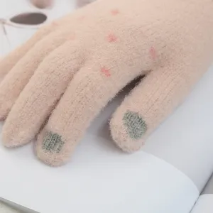 Primo piano dettagliato dei guanti invernali in maglia touch screen da donna con pois.