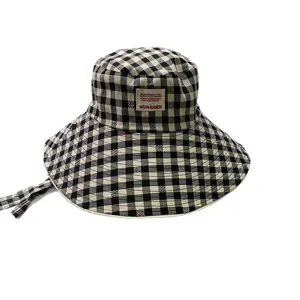 Cappello bucket a quadretti nero e bianco con bordo largo, lacci e etichetta frontale.