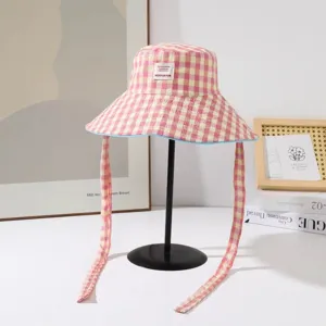 Vue rapprochée du chapeau bob rose et jaune à carreaux avec de longs liens et une étiquette.