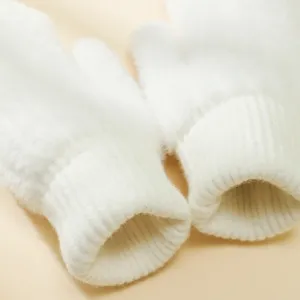 Guanti invernali in peluche bianco primo piano, morbidi polsini a coste per il freddo.