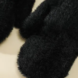 Primo piano dettagliato di morbidi guanti invernali neri in peluche con texture soffice.