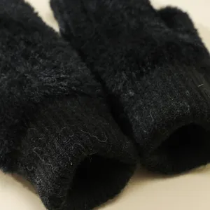Dettaglio guanti invernali neri felpati, morbida trama di peluche e polsino a coste.