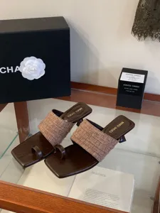 Primer plano de elegantes sandalias mules de tacón alto con tiras tejidas marrones.
