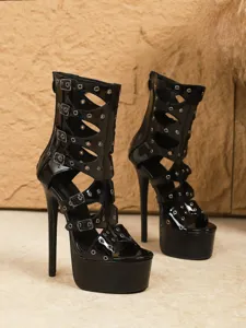 Detailed view of black patent leather high heel sandals with cut-out design and metal buckles.