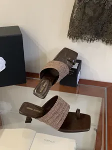 Vista detallada de elegantes sandalias marrones con puntera cuadrada y tira texturizada.