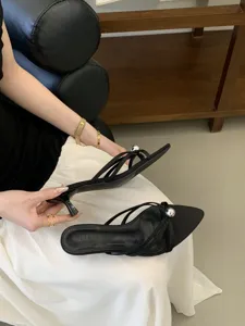 Detailansicht der schwarzen spitzen High-Heel-Pantoletten mit silberner Kugel und Riemen.