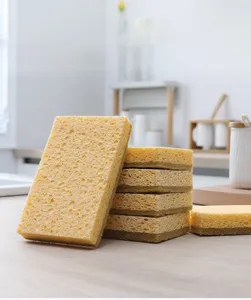 Detailed close-up of double-sided kitchen cellulose sponge and scouring pad on wooden table.