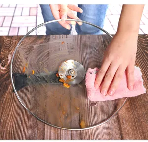 Detail shot showing a pink coral fleece dish cloth cleaning greasy cookware surface effectively.