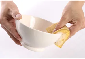 Close-up detail view of double-sided sisal wood pulp sponge cleaning bowl in kitchen.