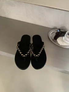 Zwarte platte teenslipper sandalen voor dames met elegante gouden studs. Ideaal voor de zomer.