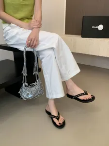 Detailopname van platte teenslipper sandalen voorzien van stijlvolle metalen klinknagels.
