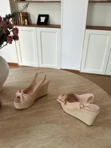 Vista dettagliata di sandali con zeppa beige e piattaforma in corda con fiocco chic.