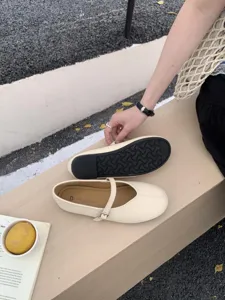 Beige flache Mary Jane Schuhe mit runder Kappe im Detail, Sohlenstruktur und Riemen.
