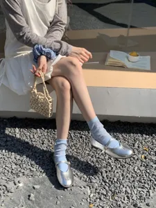 Detaillierte Nahaufnahme von silbernen Metallic Mary Jane Schuhen mit blauen Socken.