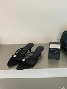 Detailansicht schwarzer Pantoletten mit spitzem Zeh, Absatz und schicker silberner Metallkugel.