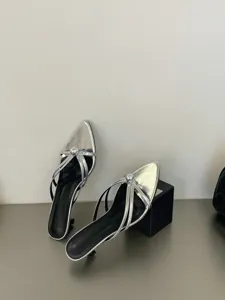 Detailaufnahme von silbernen spitzen Stiletto Mules mit metallischem Ring-Verschluss.