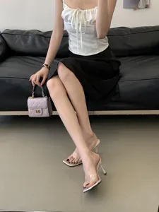 Detail shot of clear high heel mules paired with elegant summer outfit, showcasing slim heels.