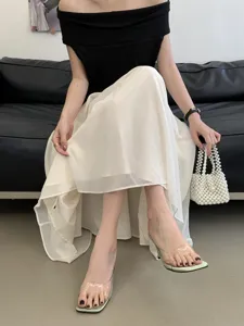 Transparent high heel mules detail shot, featuring clear strap and elegant skirt pairing.