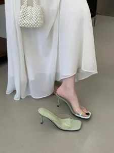 Detail shot of elegant light green stiletto mules with transparent strap for summer dresses.