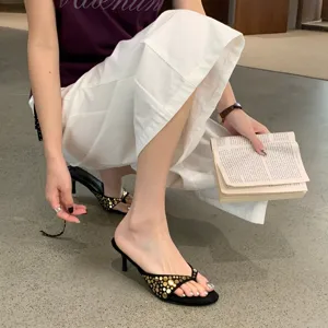 Sandalias elegantes de tacón alto y tiras en ante negro con tachuelas doradas.