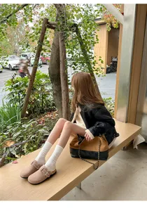 Detailansicht von gefütterten Pantoletten mit Socken im Außenbereich auf Holzsitzbank.