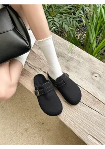 Gemütliche gefütterte schwarze Clogs mit Schnallendetail, getragen mit weißen Socken.