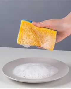 Close-up shot of wood pulp cleaning sponge generating rich foam for kitchen dishwashing.
