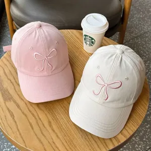 Berretti da baseball rosa e beige con delicati fiocchi ricamati su corone morbide e stile.