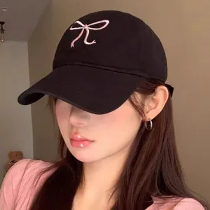 Dettaglio in primo piano del cappellino nero con grazioso fiocco ricamato rosa trendy.