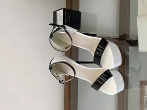 Detail shot of black and white patent leather platform high heels with ankle strap and stiletto heel.