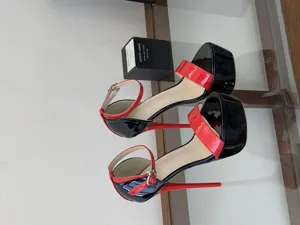 Black and red patent leather platform high heels with ankle strap and stiletto heel.