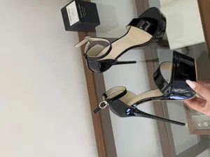 Black patent leather platform high heels with stiletto heel and adjustable ankle strap.