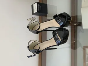 Black patent leather platform high heels detail showing stiletto heel and ankle strap.