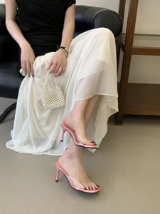Detail shot of pink transparent high heel sandals, stylish summer footwear for women with skirt.