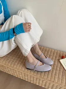 Nahaufnahme hellvioletter Mary Jane Flachschuhe kombiniert mit weißer Hose auf Rattanbank.
